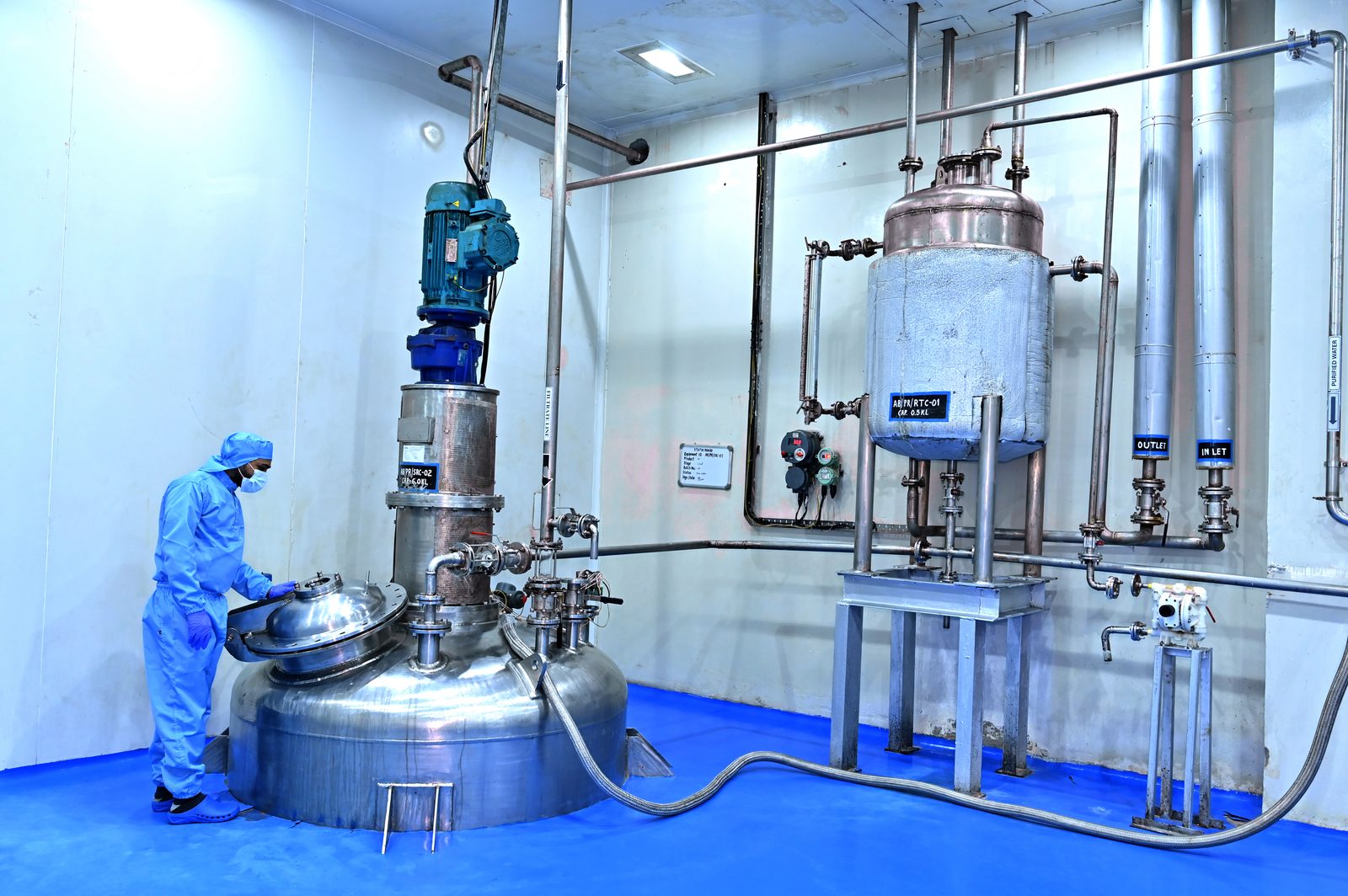 Technician opening a stainless steel reactor in the manufacturing area